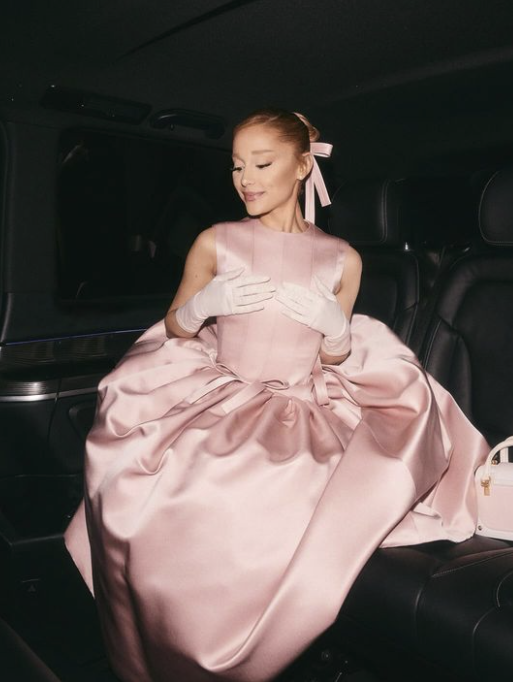 Ariana Grande The American singer dazzled in a dusty pink dress by Thom Browne. Alongside her co-star Cynthia Erivo, she paid homage to her new film project, Wicked (and her character Glinda), with her outfit. The sleeveless piece featured a high neckline and a decorative bow at the hip, an element mirrored in her hairstyle. She completed the look with white gloves and two-tone pink and white heels. This ensemble is an ideal choice for women who adore the coquette style.